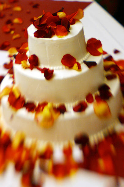istock Tiered Wedding Cake Covered with Red and Yellow Flower Petals 185073865
