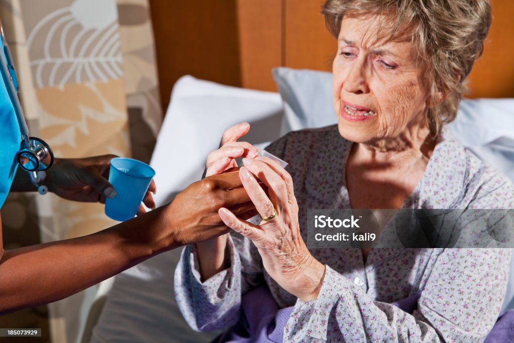 Infermiere dando farmaco per donna anziana in ospedale camera - Foto stock royalty-free di 80-89 anni