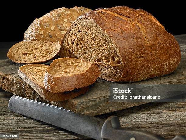 Два Loaves Темного Хлеб С Старый Нож — стоковые фотографии и другие картинки Батон - Батон, Без людей, Выпекать