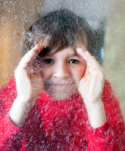 istock Child peering thru winter frosted window 185075180