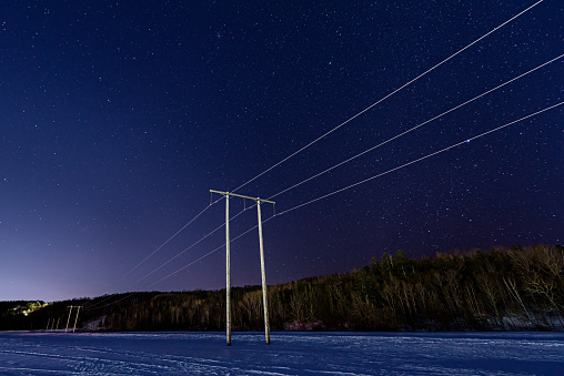 Electric transmission tower and lines with starry night sky background