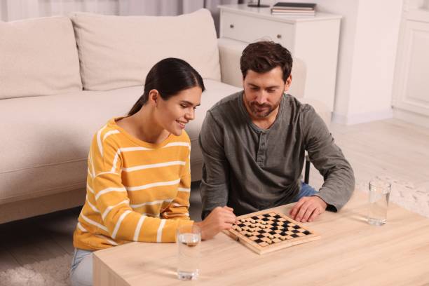 istock Happy couple playing checkers at coffee table in room 1850761308