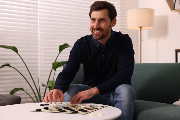 istock Happy man playing checkers on sofa at home 1850763400