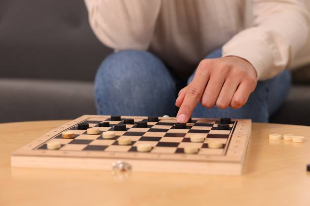 istock Woman playing checkers at wooden table, closeup 1850768079