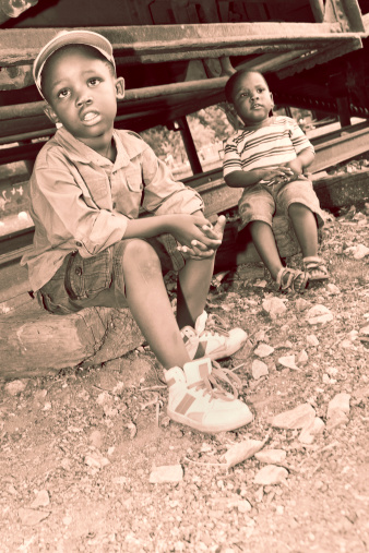 Little boys on a railway track, looking full of despair and unhappy; sepia tone