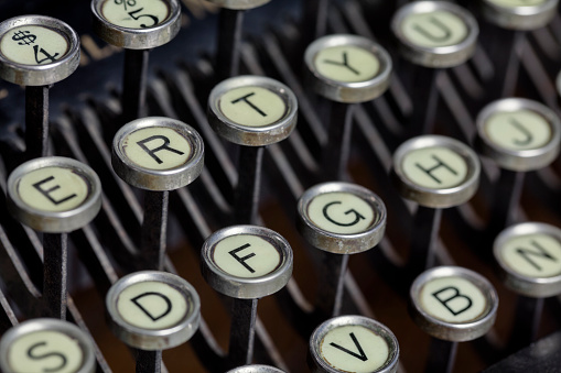 An antique black manual typewriter keyboard with its round keys was common in offices before the invention of the electric typewriter.