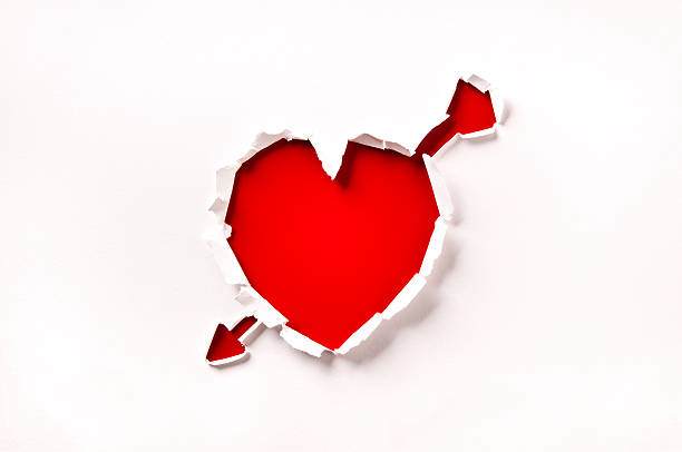 giorno di san valentino, cuore e freccia rossa foro nella carta - arrow heart shape isolated on white valentines day foto e immagini stock