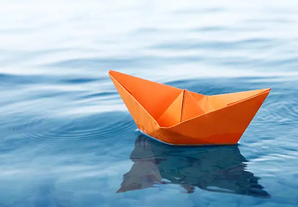 Origami paper boat floating in the sea.