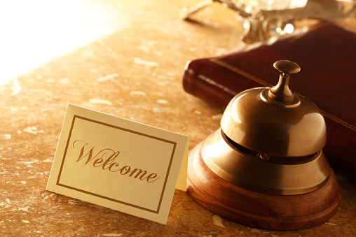 A service bell and a welcome card at a hotel desk.