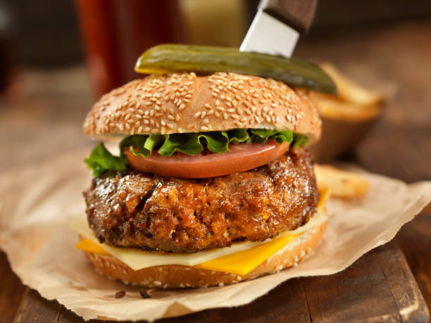 Sirloin Steak Burger Handmade Top Sirloin Cheese Burger with Lettuce, Tomato, French Fries and a Steak Knife Holding it all Together -Photographed on Hasselblad H3D2-39mb Camera salisbury steak stock pictures, royalty-free photos & images