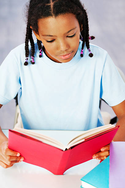 istock Serious little girl reading a book. 185080388