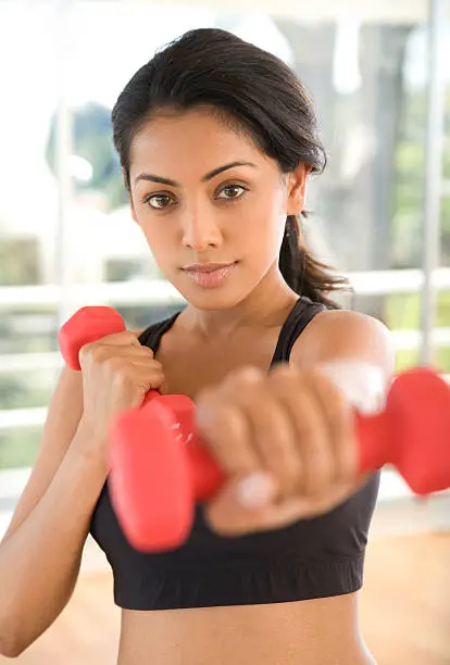 A beautiful Indian woman exercising with hand weights.