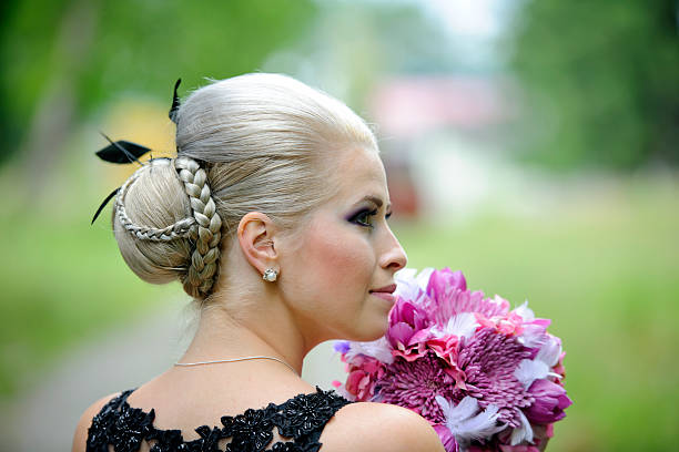 woman with beautiful hairstyle side view; woman with beautiful hairstyle holding flower bunch. braided buns stock pictures, royalty-free photos & images