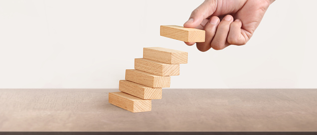 Hand liken business person stepping up a toy staircase