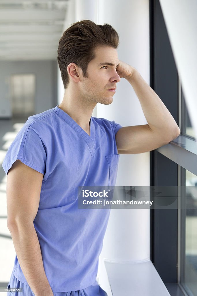 Jeune homme en bleu gommages - Photo de Se tenir la tête entre les mains libre de droits