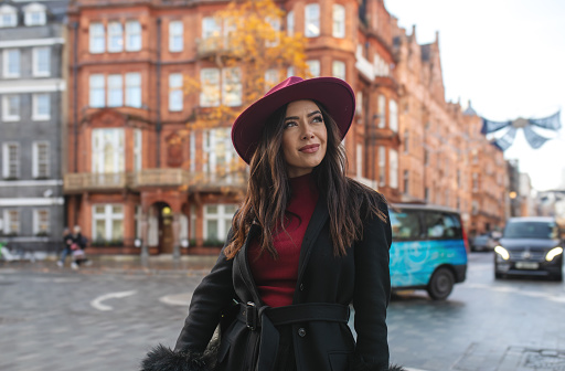 Fashionable  Woman in Red Hat Against Iconic Backdrop essence of city chic with this portrait of a stylish and beautiful young woman wearing a red hat enjoy in the iconic streets of London on a cold winter day. The backdrop features the iconic streets of Soho, Mayfair, and Kensington. This captivating stock photo is ideal for conveying urban style and sophistication. Perfect for fashion blogs, lifestyle magazines, and social media content seeking to showcase modern elegance in the heart of London. Portrait, Stylish, Beautiful, Urban young woman, Red hat, London's iconic streets, Sunny day,  City chic, Contemporary fashion, Historic landmarks Urban style, Sophistication, Fashion blogs, Lifestyle, Social media.