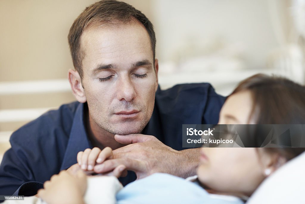 Please make her better Young worried father praying next to his sick daughter as she lies in a hospital bed Praying Stock Photo