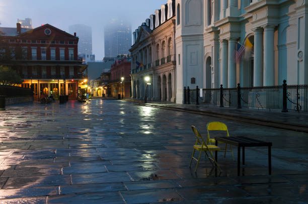 A courtyard at dusk with a card table and two yellow chairs Jackson Square in the night after a rain.New Orleans Louisiana jackson square stock pictures, royalty-free photos & images