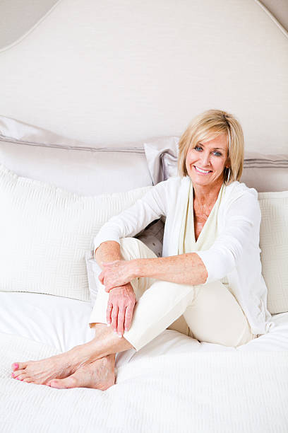 allegro donna matura rilassante su un letto - mature women beautiful senior women menopause foto e immagini stock