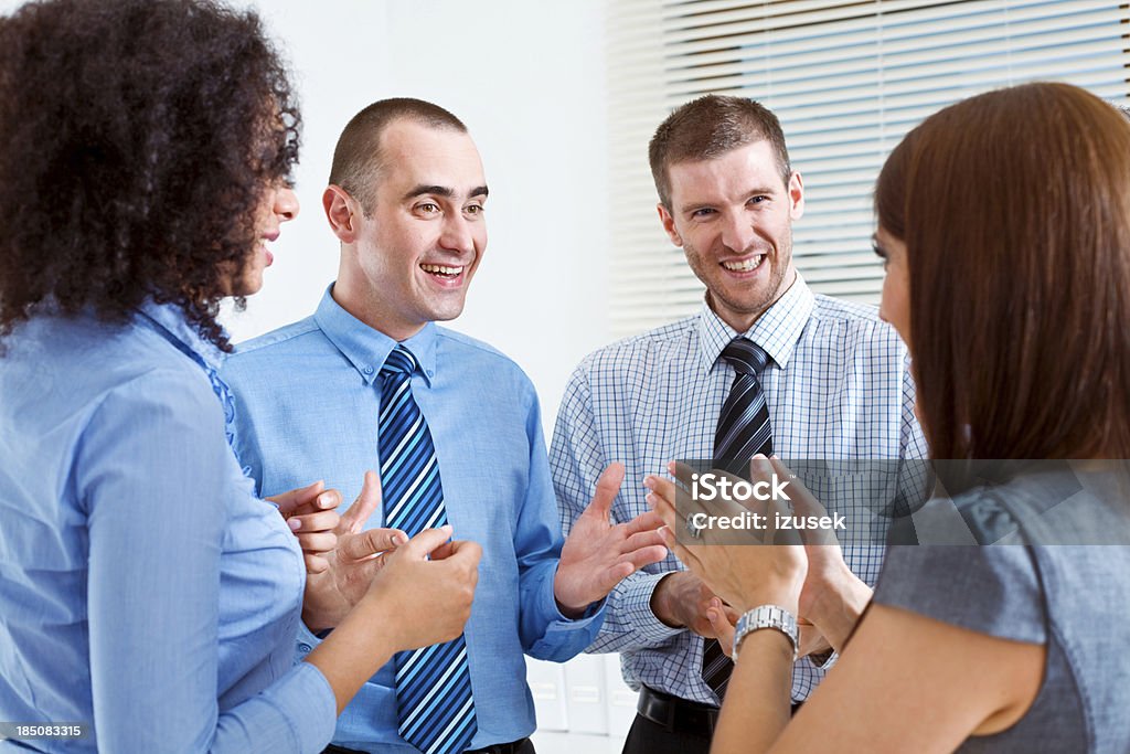Business Team discussing Four smiling business people standing in an office and talking. 25-29 Years Stock Photo