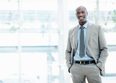 Smartly dressed executive smiling as he stands at his workplace - Copyspace