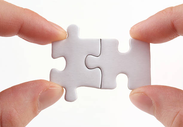istock Two sets of fingers holding two puzzle pieces together 185083507