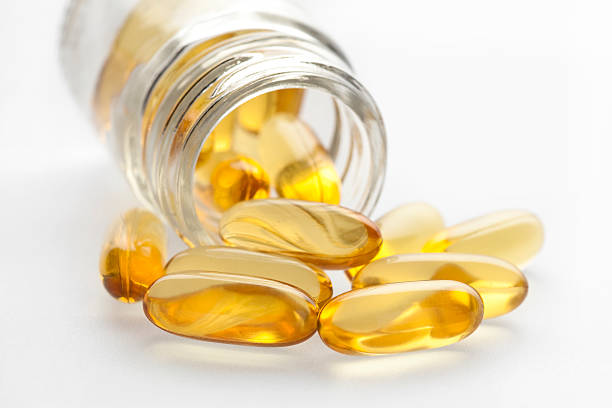 омега - 3 рыбий жир в капсулах и бутылка - fish oil cod liver oil nutritional supplement pill стоковые фото и изображения