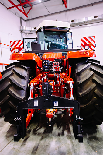 Rear view of modern agricultural tractor in hangar. Hydraulic hitch. Hydraulic lifting frame. Rear mechanism for attaching trailed equipment