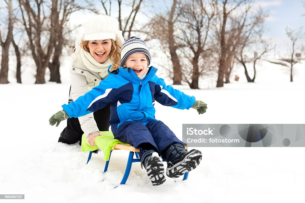 Poco niño y su madre paseos en trineo en la nieve - Foto de stock de Empujar libre de derechos