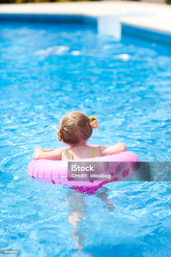 Petite fille de flotter avec anneau de natation dans la piscine extérieure - Photo de 2-3 ans libre de droits