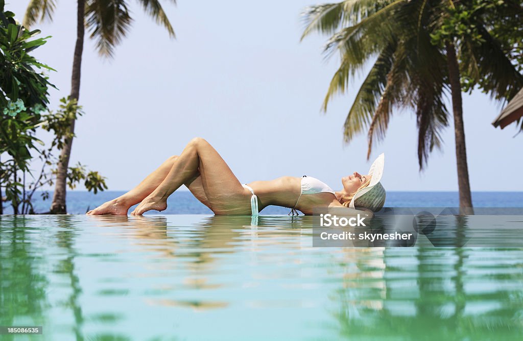 Piękna kobieta opalać się na brzegu basenu. - Zbiór zdjęć royalty-free (Kobiety)