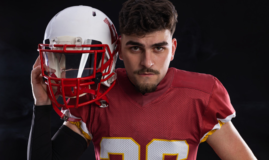 American football player teenager on black background.