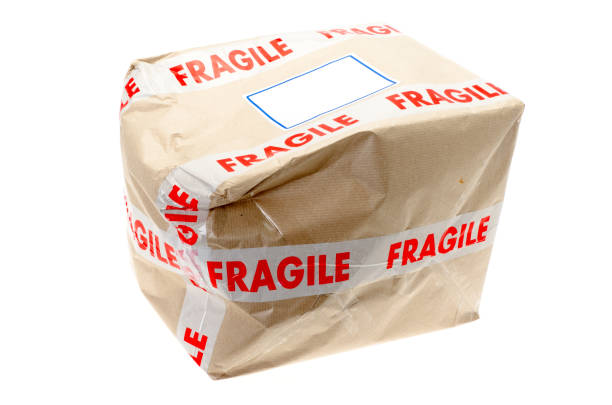 Damaged cardboard box that was covered with fragile tape - studio shot with a white background