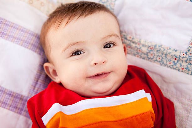 istock Color Image of Smiling Baby Boy Lying on Patchwork Quilt 185087366
