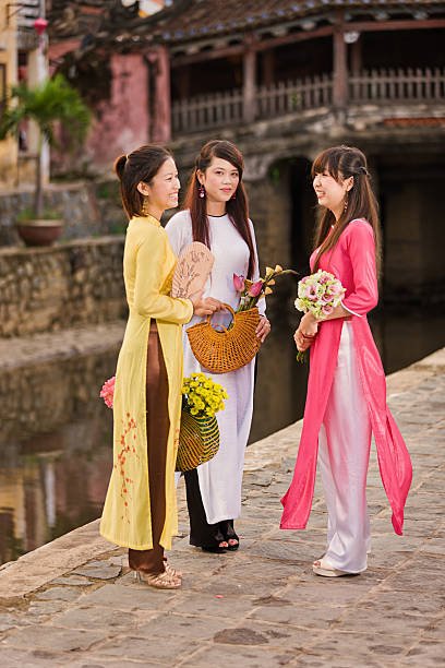 Portrait of three young Vietnamese women wearing ao dai "Portrait of three young Vietnamese women  wearing ao dai, Hoi An, Vietnam. Hoi An is situated on the east coast of Vietnam. Its old town is a UNESCO World Heritage Site because of its historical buildings." ao dai stock pictures, royalty-free photos & images