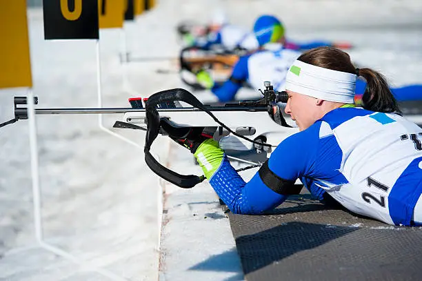 Side view of young female biathlon competitor shooting in lying position