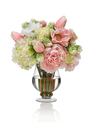 A large spring bouquet of mixed flowers in a footed round glass vase. It contains peonies, hydrangeas and tulips. Shot against a bright white background. There is a path which may be used to delete the reflection if desired. Extremely high quality faux flowers.