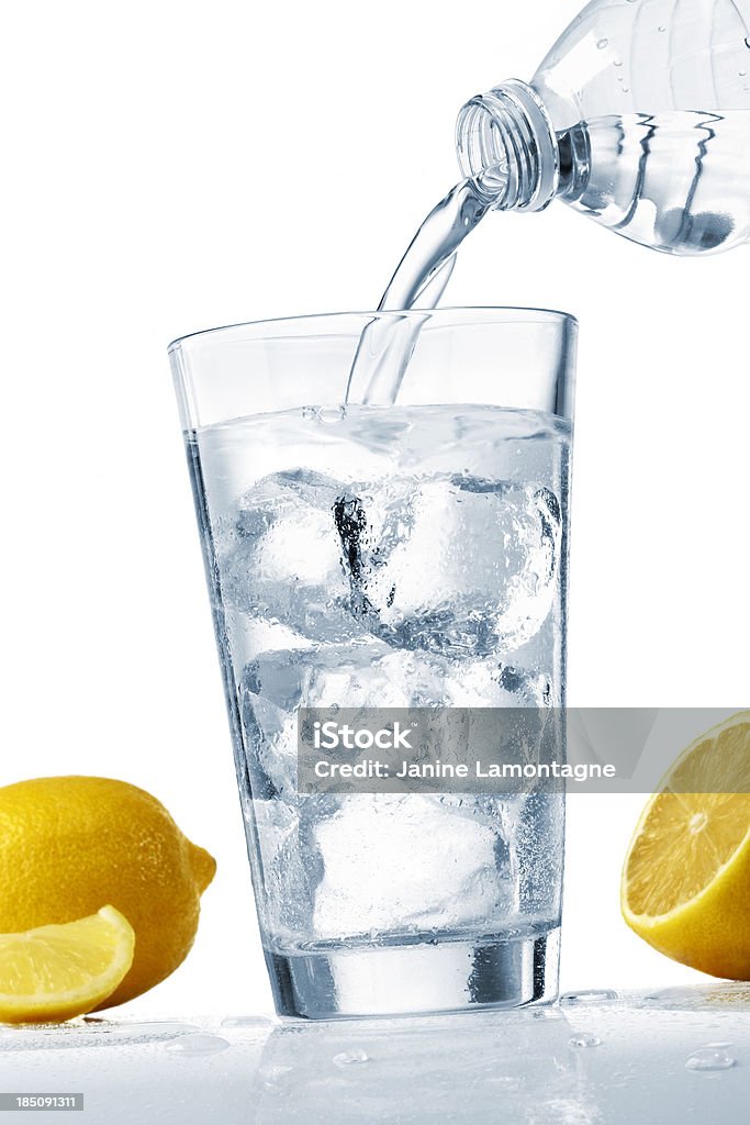 Pouring a glass of water pouring a glass of refreshing ice cold water from a plastic bottle with a lemon wedges. Artificial Ice Stock Photo