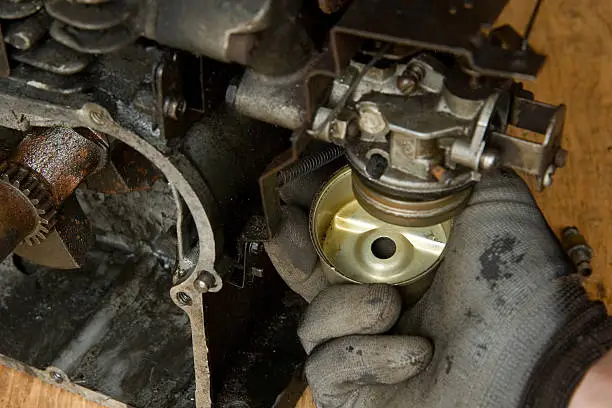 Mechanic holds the float bowl under a small gasoline engine carburetor20100221044See more in my Small Engine Repair lightbox: