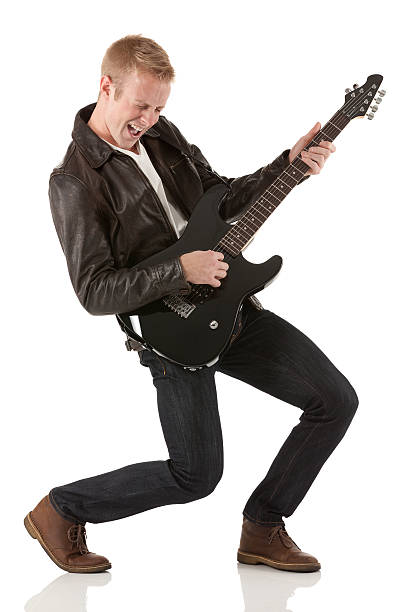 atractiva joven tocando una guitarra - isolated on white studio shot guitar young men fotografías e imágenes de stock