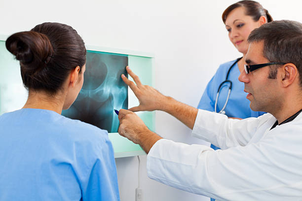 equipo de médicos estudiando imagen de rayos x - x ray image radiologist examining using voice fotografías e imágenes de stock