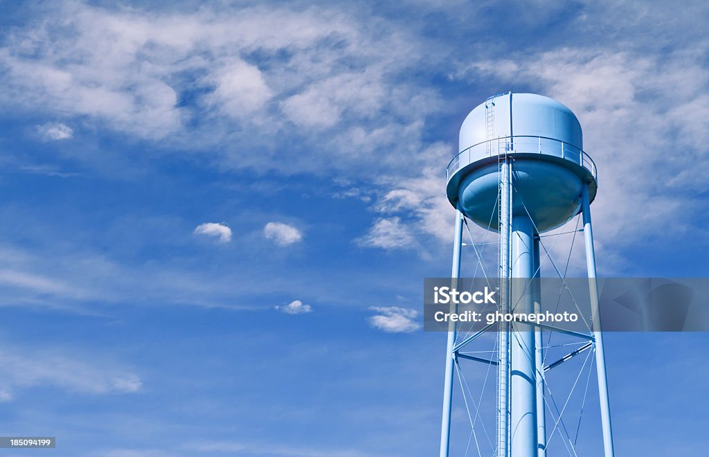 Water tower with wispy clouds in sky behind A city water tower set against a blue sky Water Tower - Storage Tank Stock Photo
