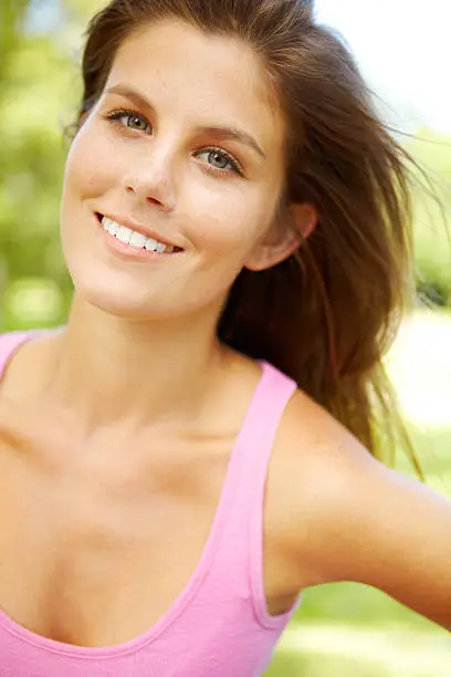 A close-up of a lovely young woman in a pink top wearing her hair loose
