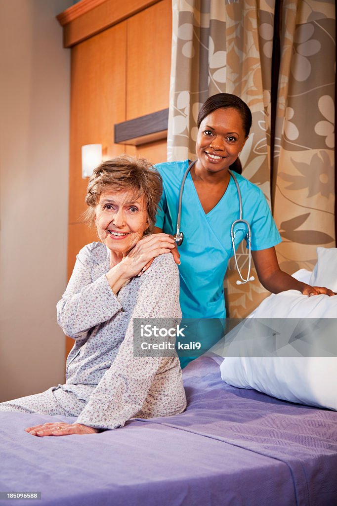 Enfermera ayudando a senior mujer en el hospital habitación - Foto de stock de Cama libre de derechos