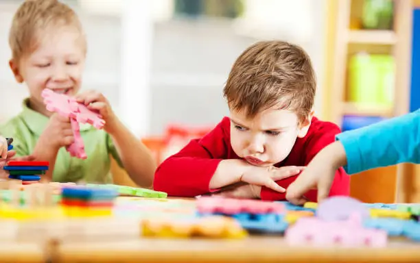 Photo of Angry little boy looking at puzzles.