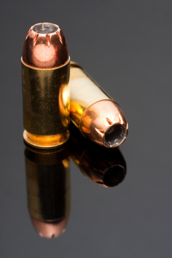 Two.45 caliber hollowpoint bullet on a reflective grey background.All images in this series...