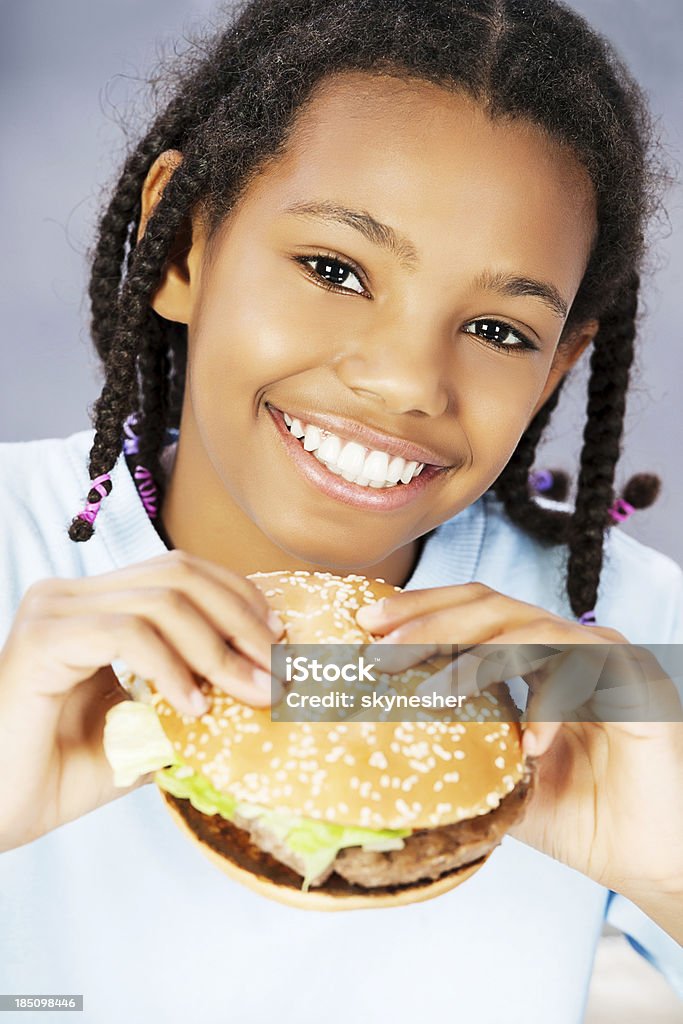 Bambina mangiare hamburger, godendo di fast food - Foto stock royalty-free di Affamato