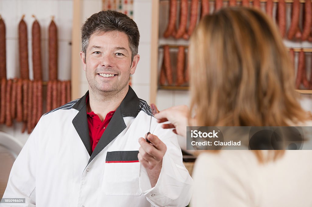 Butcher giving customer piece of sausage Sales executive with customerMore photos of sausages and butcher shop: Butcher Stock Photo