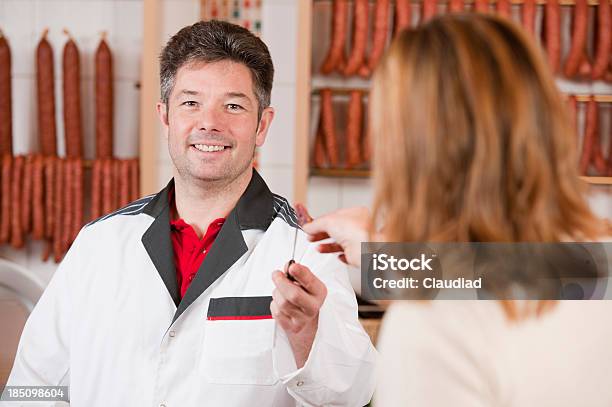 Butcher Giving Customer Piece Of Sausage Stock Photo - Download Image Now - Butcher, Butcher's Shop, Giving