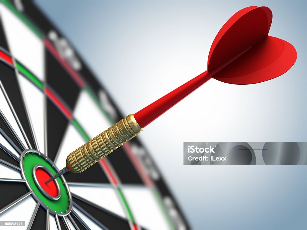 A red dart in a bulls eye target shallow depth of field shot of darts in bullseye on dartboard Dartboard Stock Photo